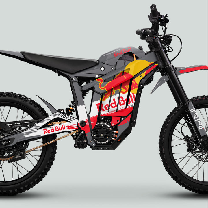 Side-view of Talaria Sting MX5 PRO Graphics Kit with Red Bull livery, showcasing integrated battery, suspension, knobby wheels, and vibrant decals for off-road electric dirt bikes.