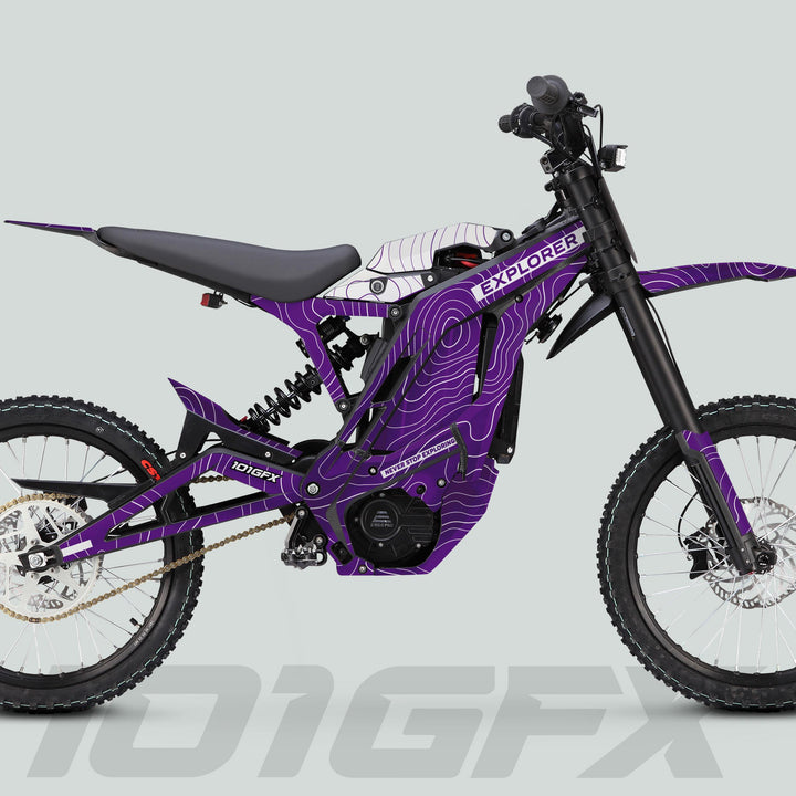 Side-profile of purple E Ride Pro SS Graphics Kit EXPLORER on an off-road electric bike with knobbly wheels, suspension, and bold branding.