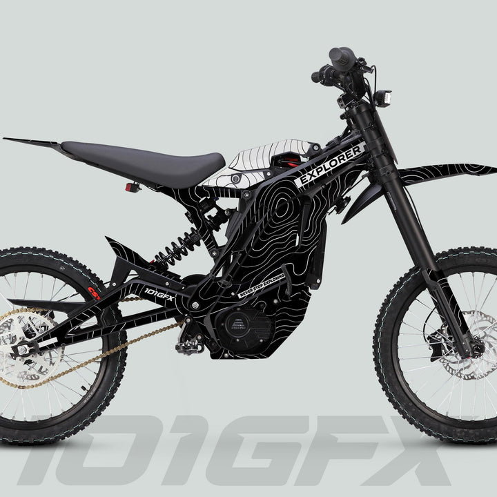 Side-view of an E Ride Pro SS Graphics Kit EXPLORER Black White on an electric off-road motorcycle, showcasing its tubular frame, suspension, and knobby tires.