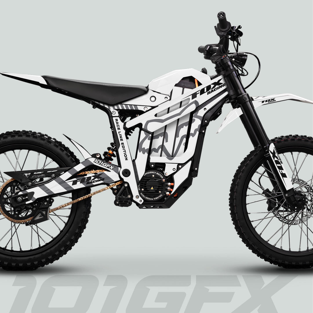 Talaria Sting MX5 PRO Graphics Kit FOX RACELINE enhances a modern electric dirt bike with distinctive white-and-black livery, knobby tires, and robust suspension.