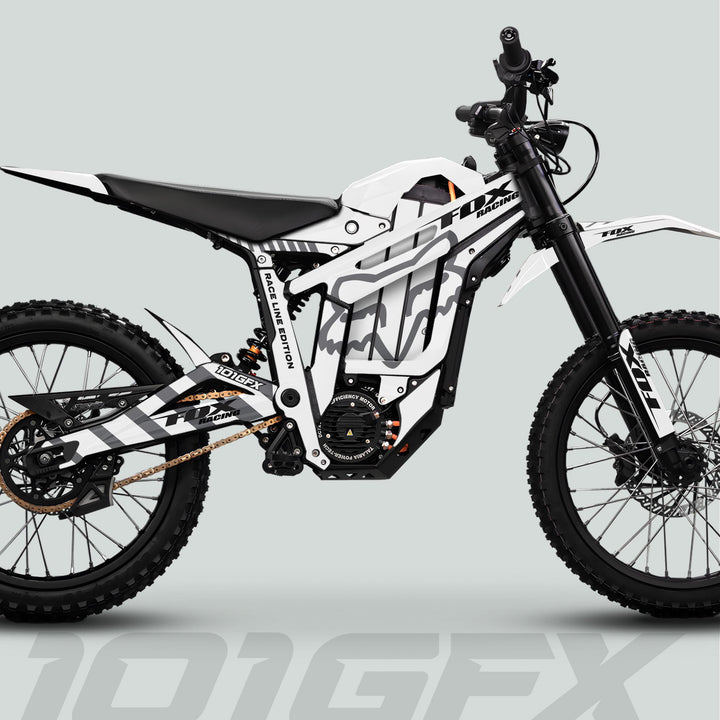 Talaria Sting MX5 PRO Graphics Kit FOX RACELINE enhances a modern electric dirt bike with distinctive white-and-black livery, knobby tires, and robust suspension.