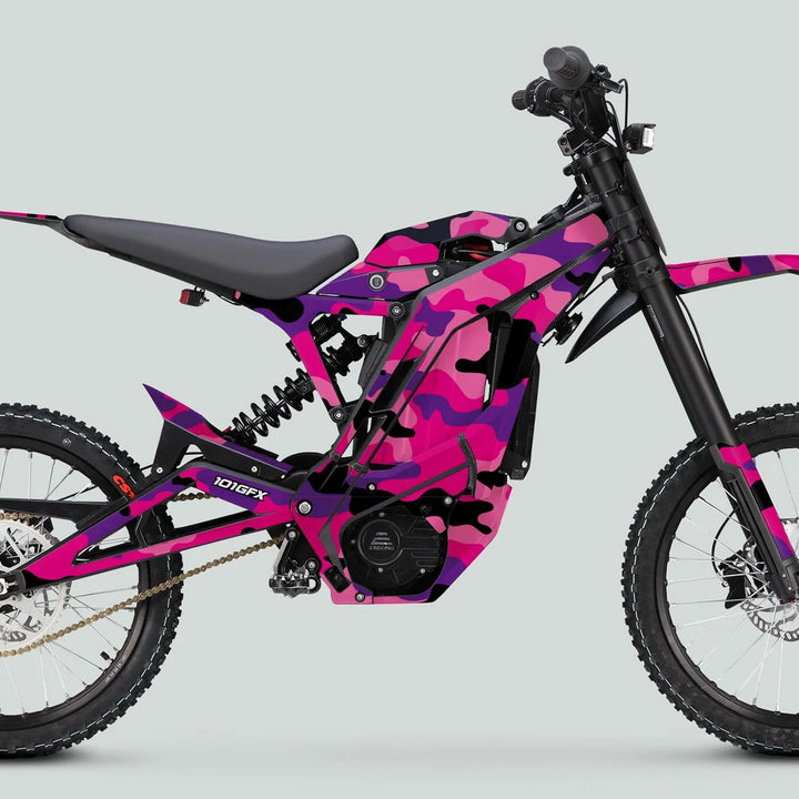 Side-view of an E Ride Pro SS Graphics Kit CAMOUFLAGE PINKY on an electric dirt bike, showcasing knobby tires, suspension, and pink camouflage design.