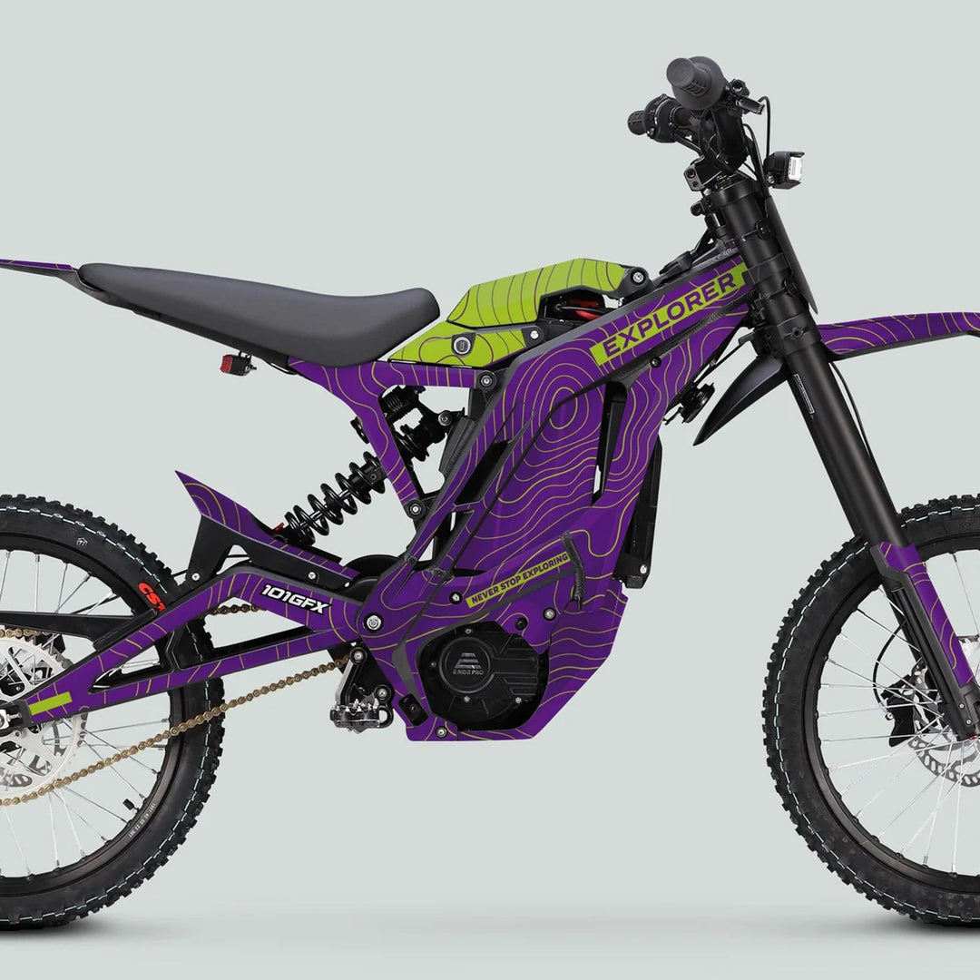 Side-profile of a full-suspension e-dirt bike with E Ride Pro SS Graphics Kit EXPLORER in purple and green, featuring bold topographic decals and EXPLORER branding.