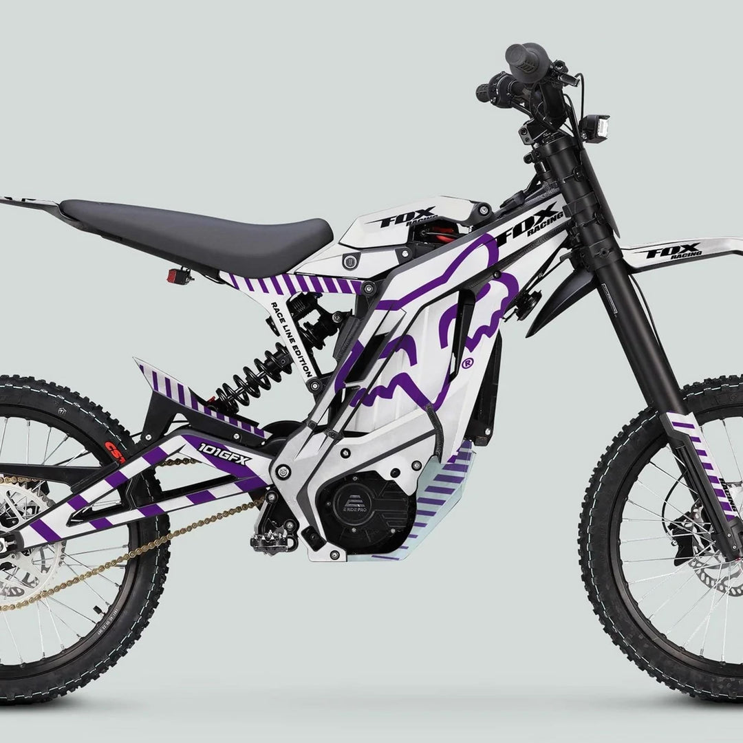Side profile of E Ride Pro SS Graphics Kit FOX Race Line White Purple on an electric dirt bike, featuring purple graphics, long-travel suspension, and knobby tires.