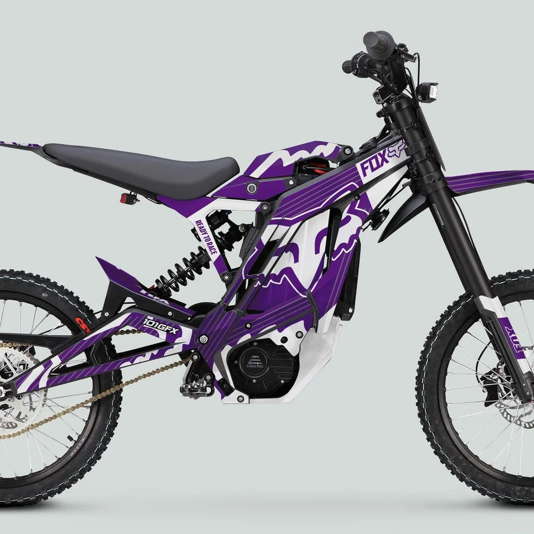 Purple-and-white off-road electric dirt bike with FOX R Stripes, featuring knobby tires, suspension forks, and electric motor; styled by Fox Racing for E Ride Pro SS Graphics Kit.