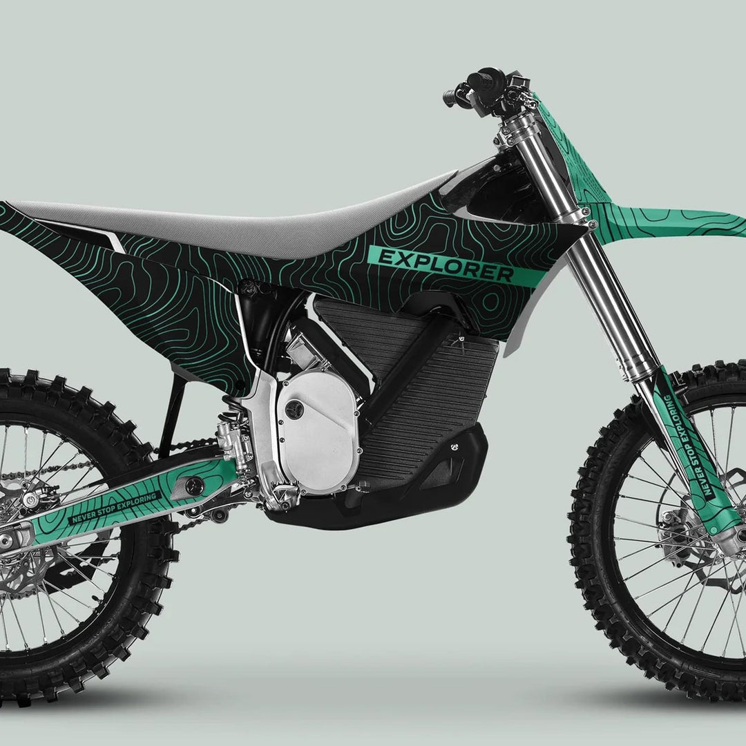 Side-profile of a dirt bike with Stark Varg Graphics Kit EXPLORER BLACK MINT Decals, showcasing knobby tires, streamlined bodywork, and electric-drive motor housing.
