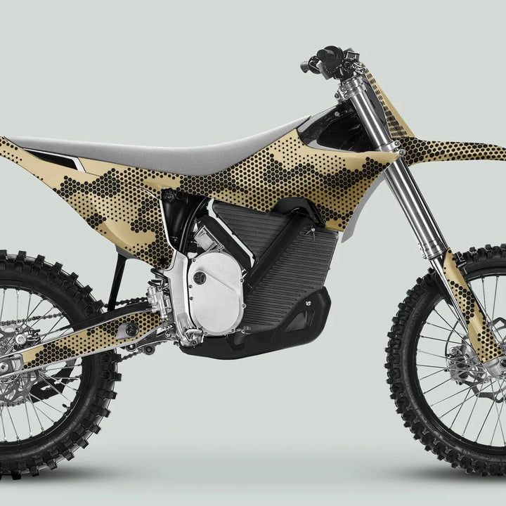 Side profile of a dirt bike featuring Stark Varg Graphics Kit HEXOCAM Sand Decals, showcasing tan-and-black hexagonal camo wrap on knobby tires and high ground-clearance frame.