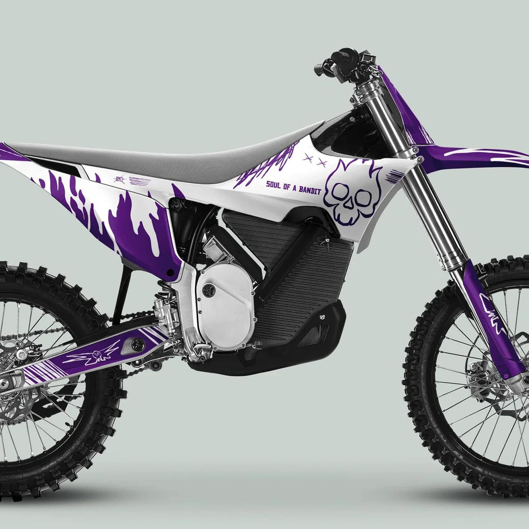 Side profile of a dirt-bike with Stark Varg Graphics Kit SOUL FLAME White Purple Decals, featuring flames, a skull, and slogan, enhancing its aesthetic.