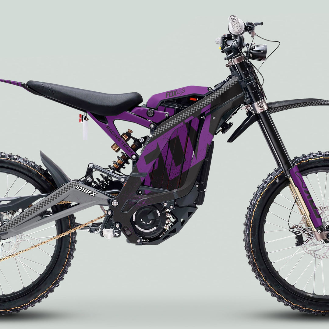 Surron Light Bee X Graphics Kit FOX DUST Black Purple on electric dirt-bike, showcasing black and purple design, knobby tires, and visible electric components against a pale grey background.
