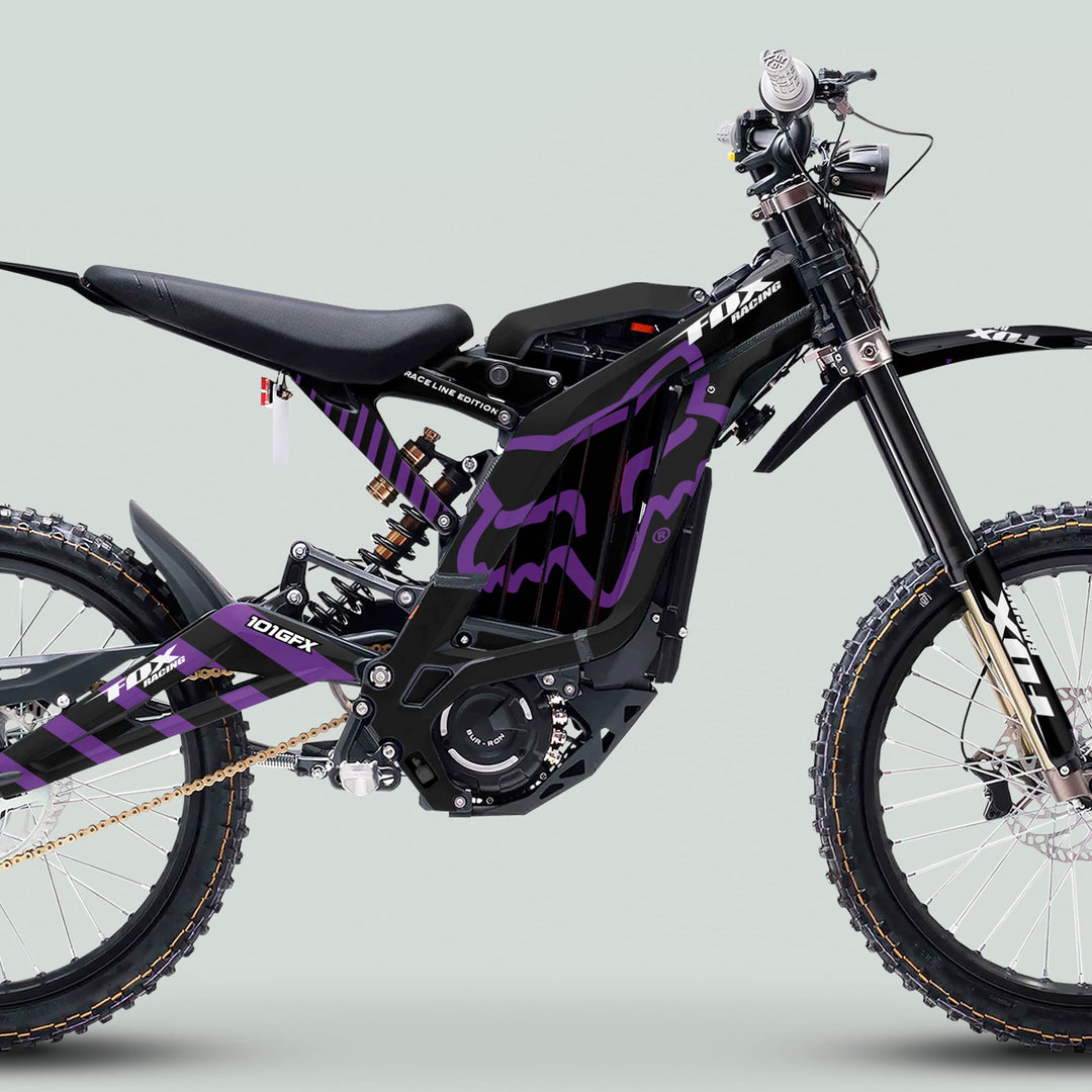 Surron Light Bee X Graphics Kit FOX RACELINE BLACK Purple on an e-dirt bike, featuring a black frame with purple graphics, spoked wheels, and knobby tires.
