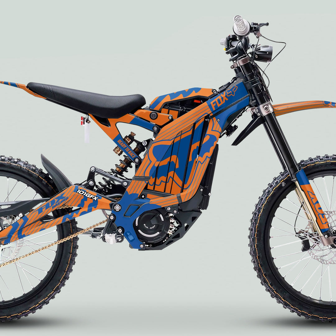 Side view of the Surron Light Bee X Graphics Kit FOX STRIPES ORANGE Blue on an electric dirt bike, highlighting its tubular frame and off-road features.