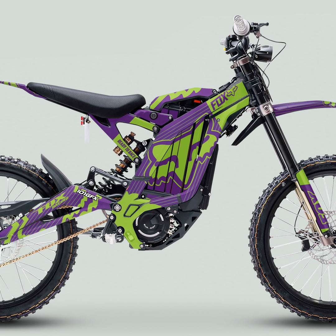 Surron Light Bee X Graphics Kit FOX STRIPES PURPLE Green, featuring striking Fox Racing graphics on an off-road electric bike with long-travel suspension and knobby tires.