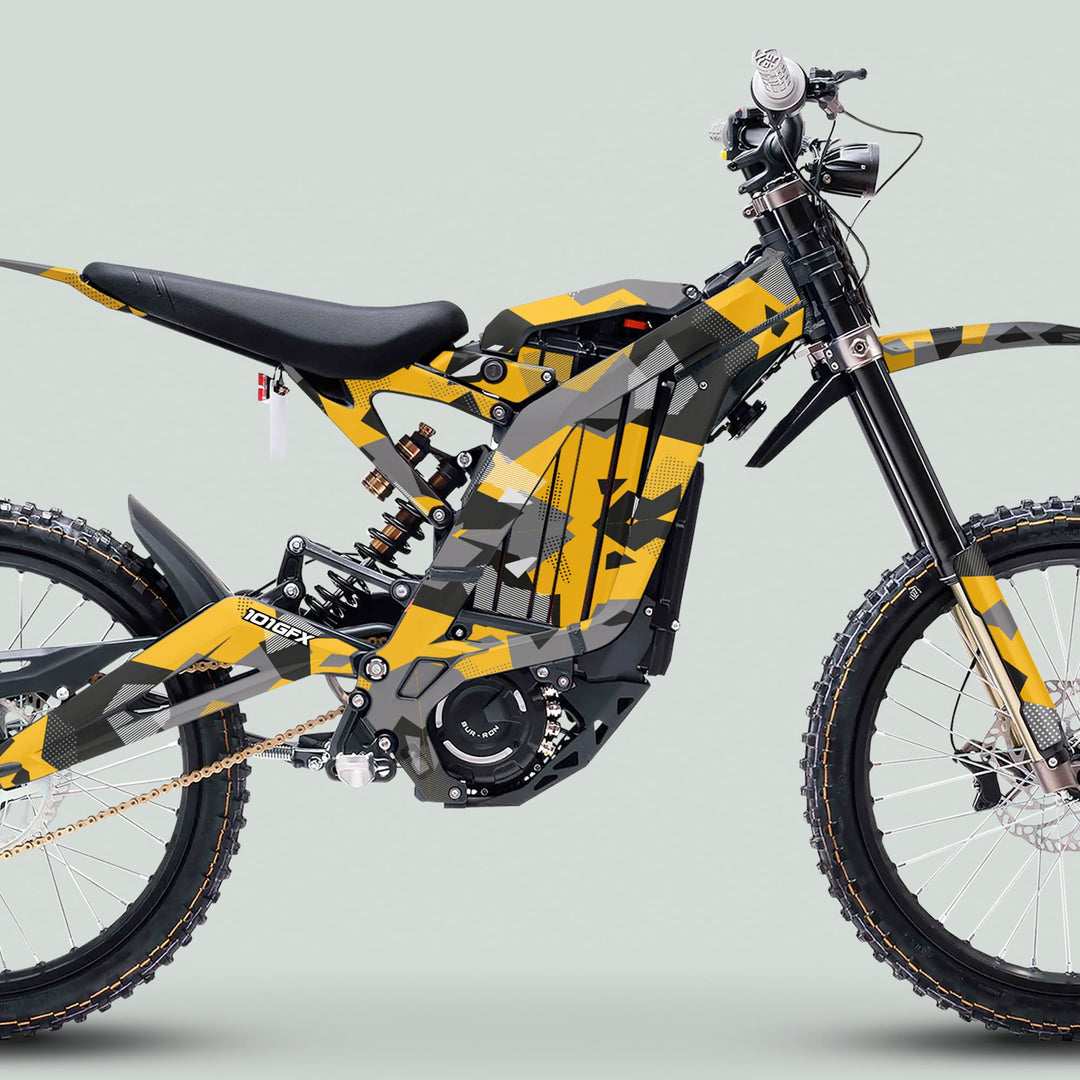 Surron Light Bee X Graphics Kit GEOTECH YELLOW on an electric off-road bike, featuring camo wrap, tubular frame, knobby tires, and disc brakes.