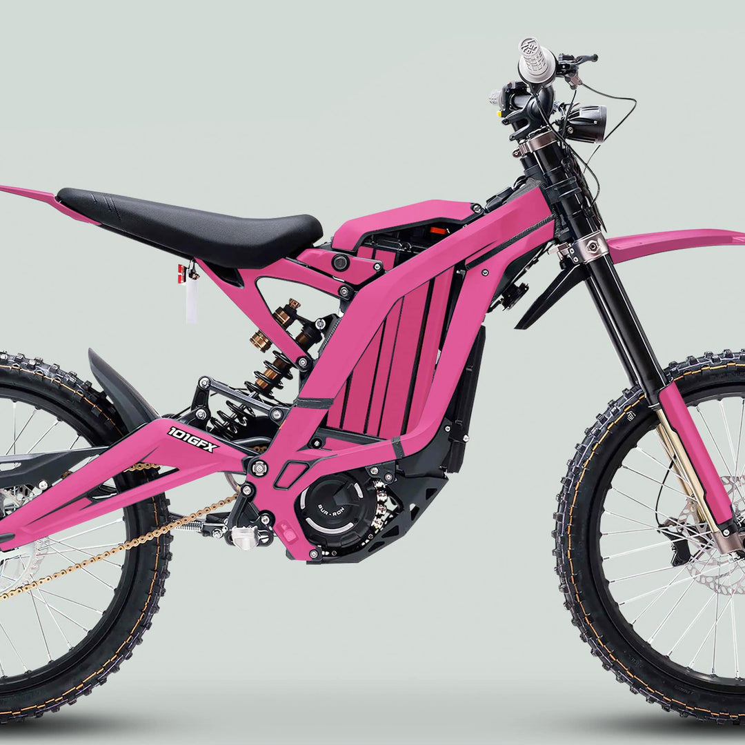 Surron Light Bee X Graphics Kit MONO COLOR Pink on an electric dirt bike, showcasing full suspension, knobby tires, and handlebar controls.