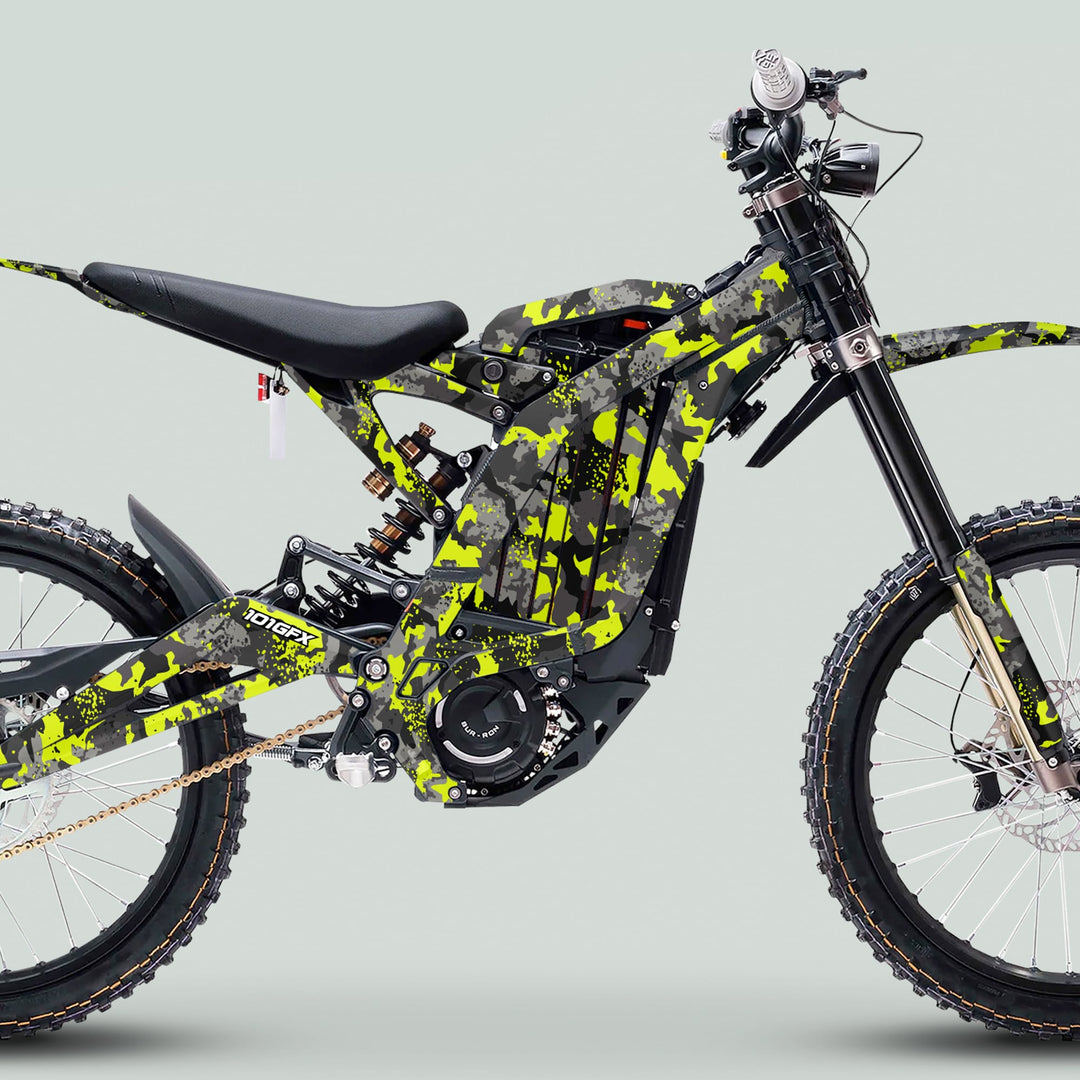 Surron Light Bee X Graphics Kit SPLAT CAMO Green on an electric dirt bike; features angular frame, knobby tires, and sleek camouflage pattern for enhanced style and protection.