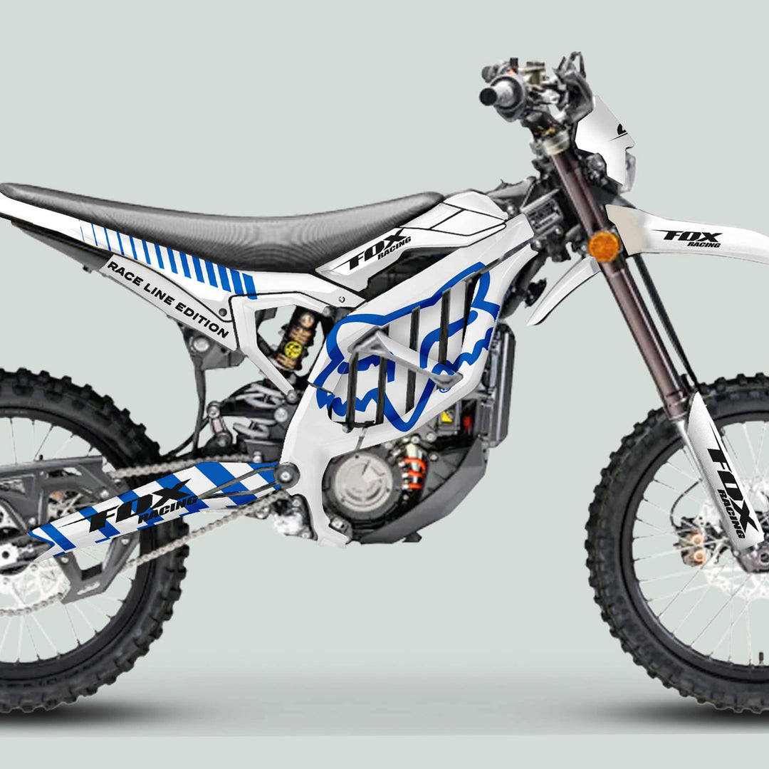 Surron Ultra Bee Graphics Kit FOX RACE LINE White Blue on a dirt bike, featuring Fox Racing graphics, knobby tires, and durable decals for enhanced style and fit.