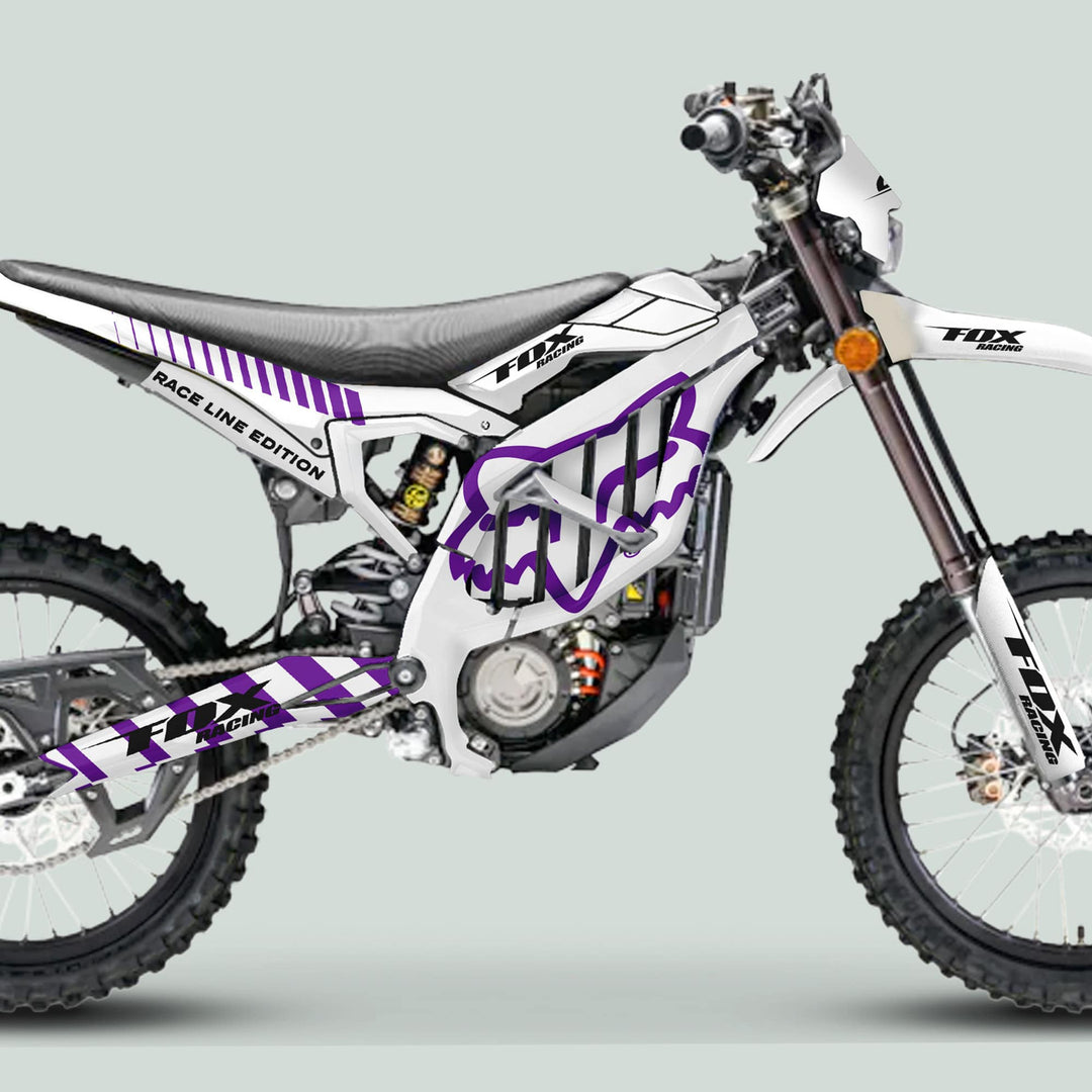 Surron Ultra Bee Graphics Kit FOX RACE LINE White Purple on a dirt bike, featuring vibrant decals, knobbly tires, and Fox Racing branding for stylish customization.