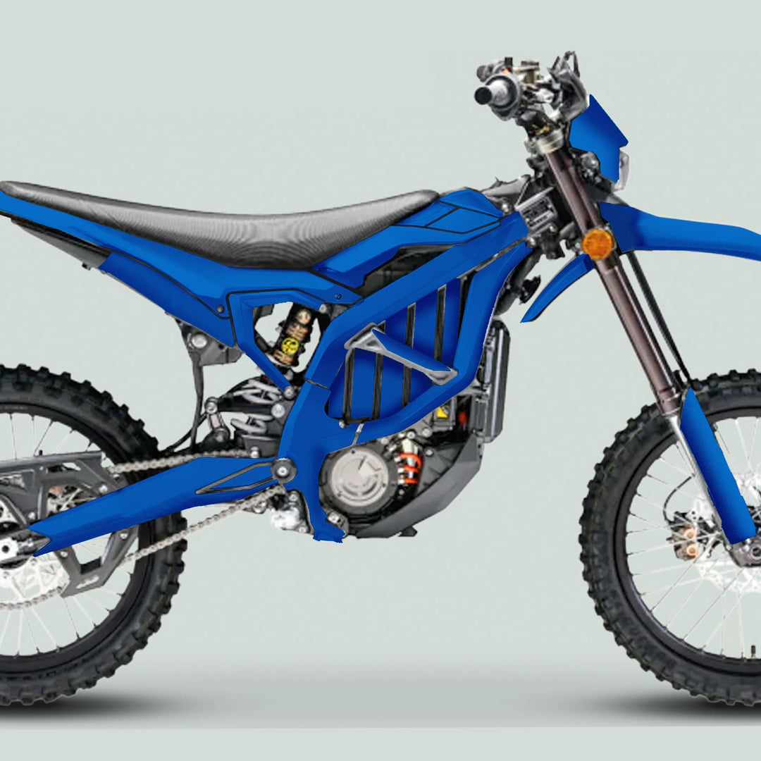 Side-profile of a Surron Ultra Bee Graphics Kit in SOLID COLOR BLUE, showcasing its sleek design on an off-road motorcycle's electric powertrain and knobby tires.
