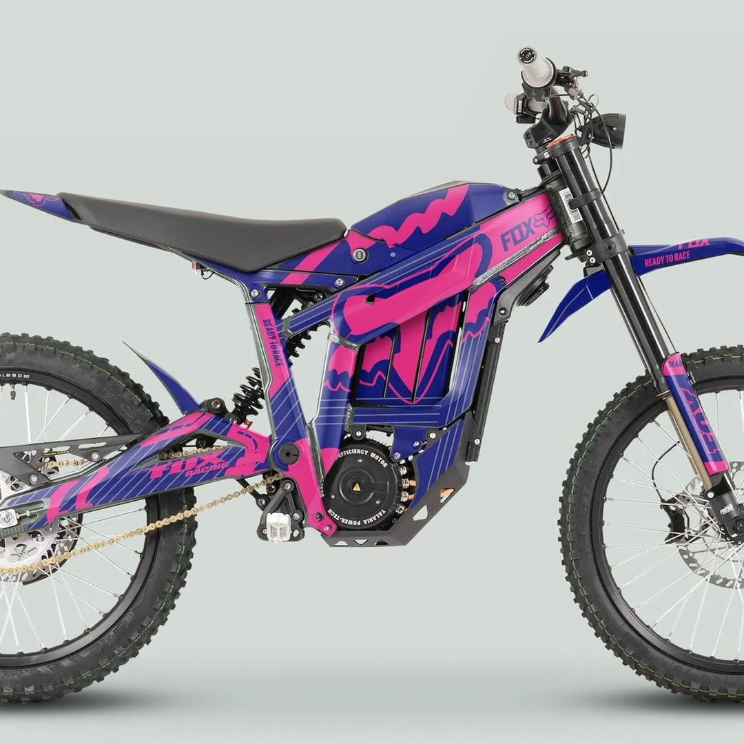 Side view of Talaria Sting MX3 MX4 Graphics Kit FOX STRIPES Navy Magenta on an off-road electric dirt bike, featuring pink and blue livery with rugged components.
